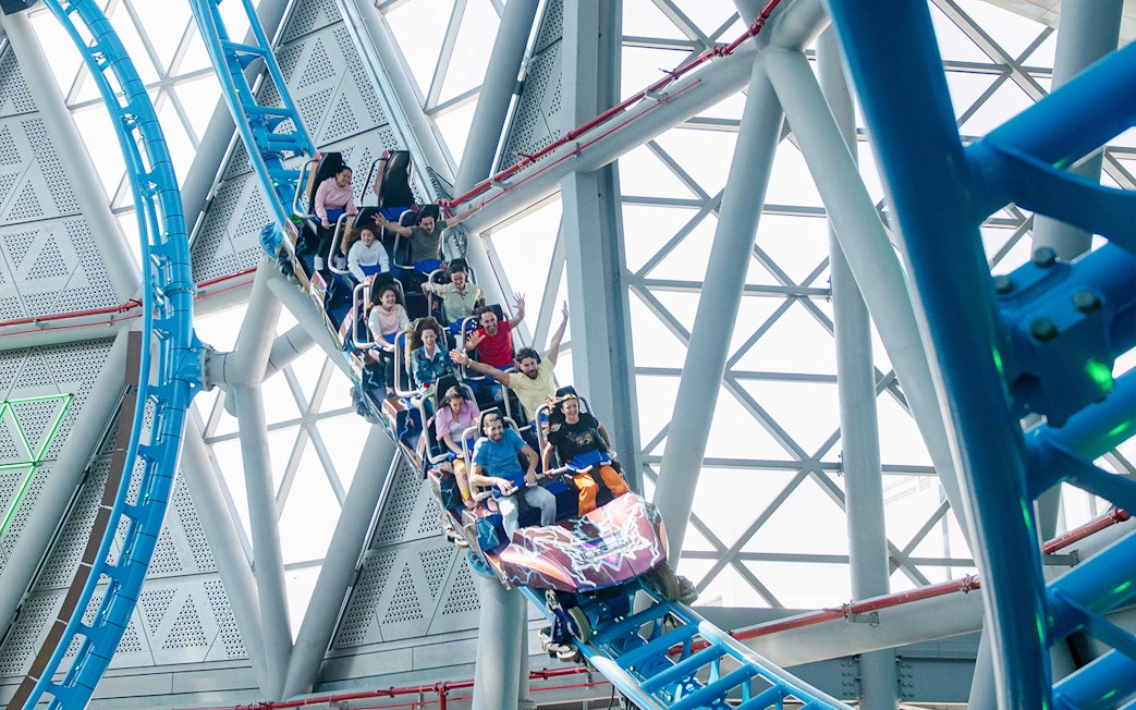 Riders on The Storm Coaster Dubai during a thrilling loop inside a modern structure.