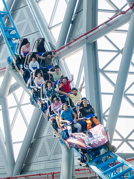 Riders on The Storm Coaster Dubai during a thrilling loop inside a modern structure.