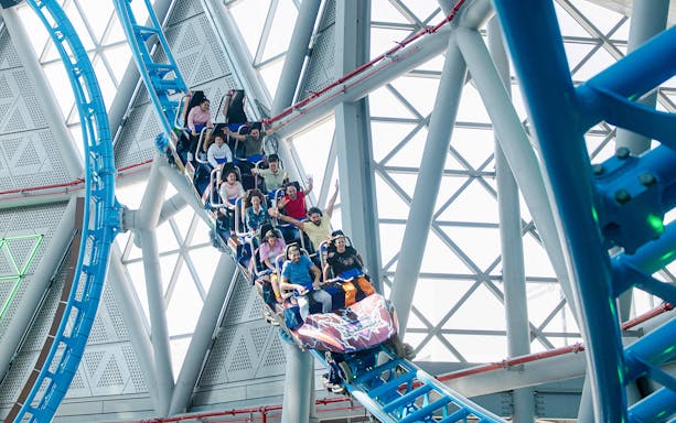Riders on The Storm Coaster Dubai during a thrilling loop inside a modern structure.