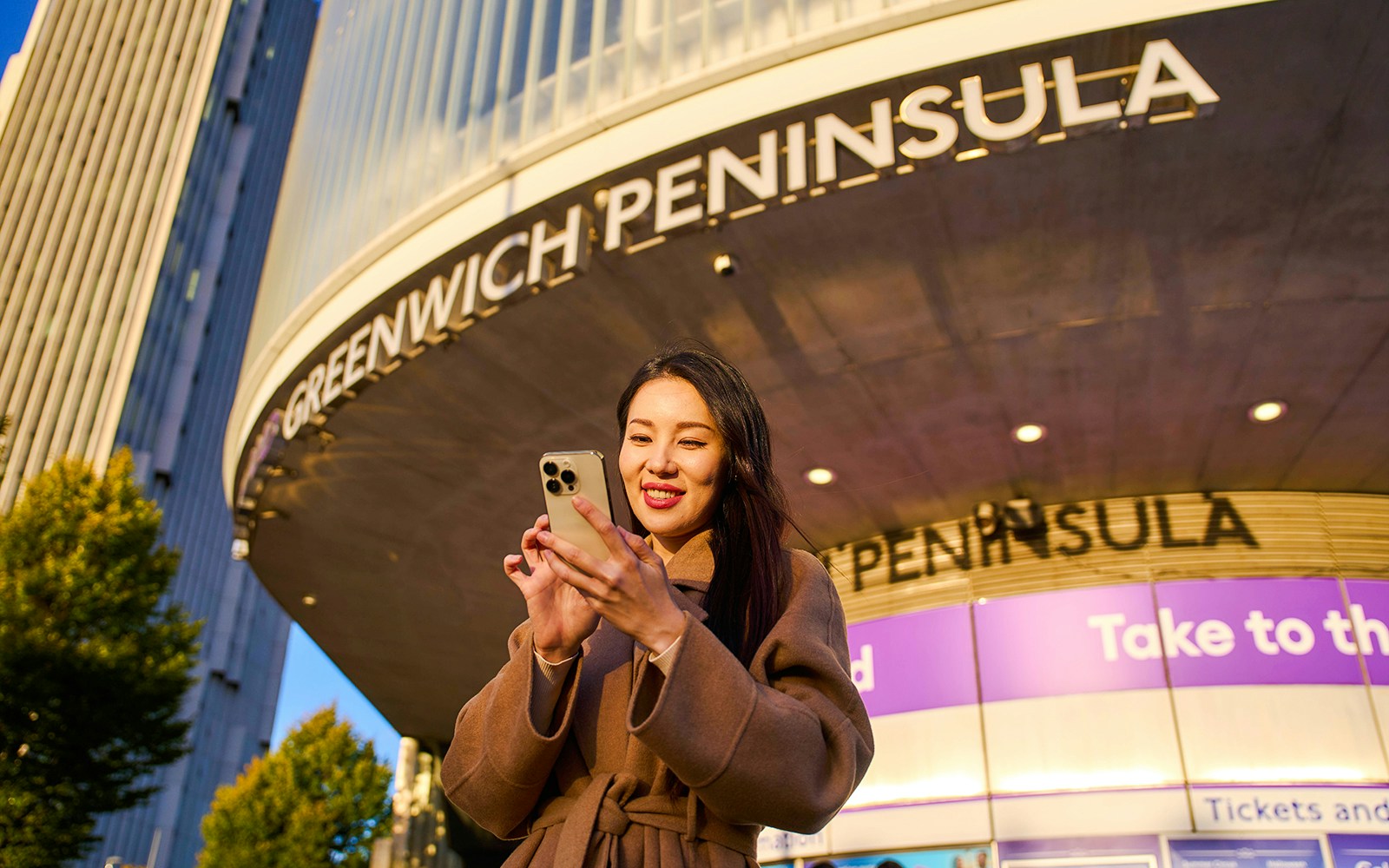 Guest using phone at Greenwich Peninsula, London near IFS Cloud Cable Car.