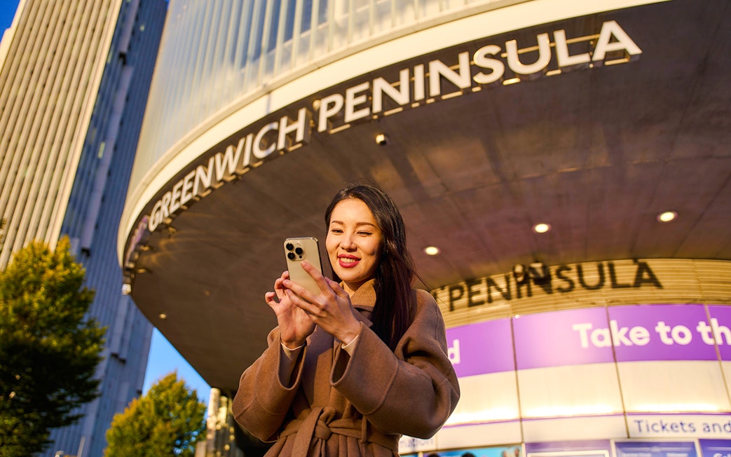 Guest using phone at Greenwich Peninsula, London near IFS Cloud Cable Car.