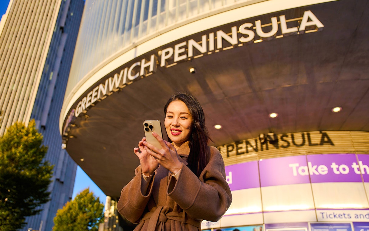 Guest using phone at Greenwich Peninsula, London near IFS Cloud Cable Car.