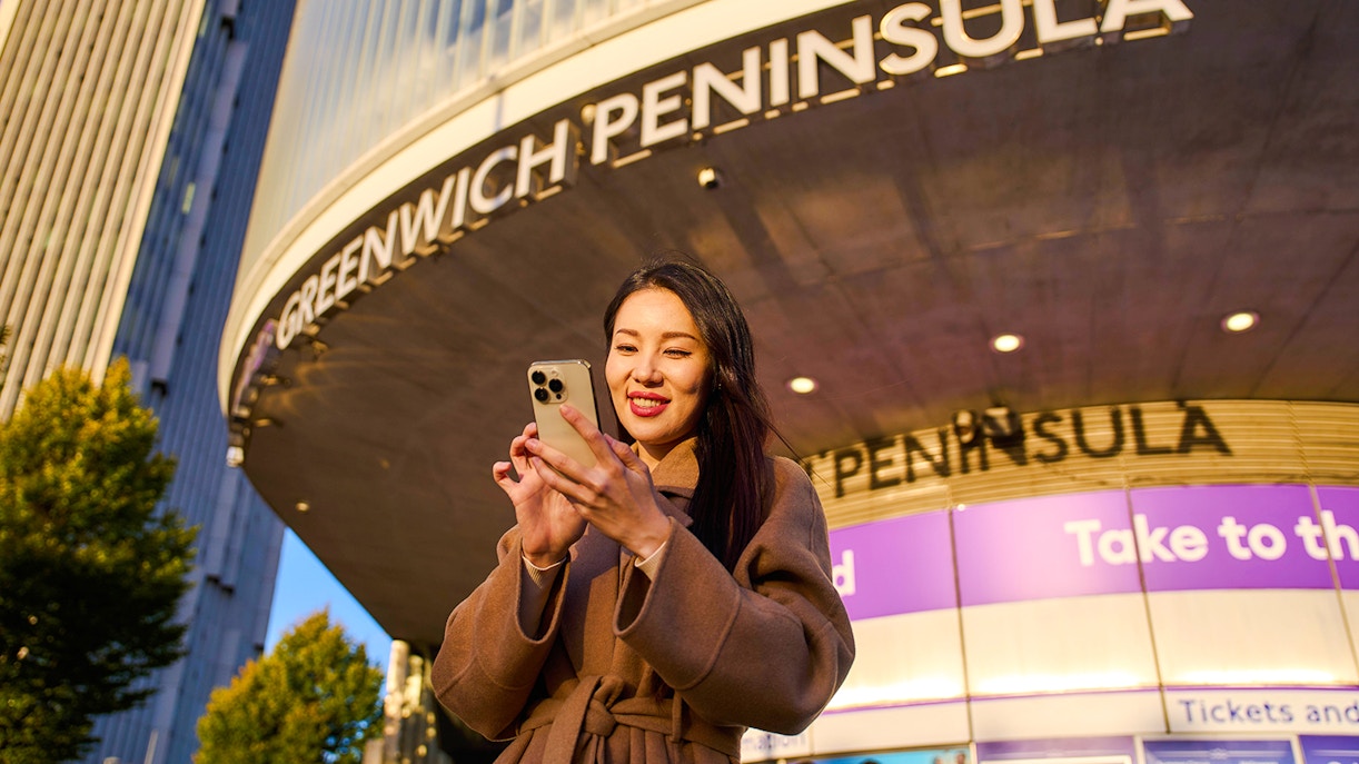 Guest using phone at Greenwich Peninsula, London near IFS Cloud Cable Car.