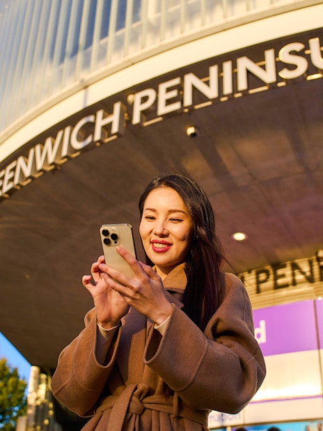 Guest using phone at Greenwich Peninsula, London near IFS Cloud Cable Car.