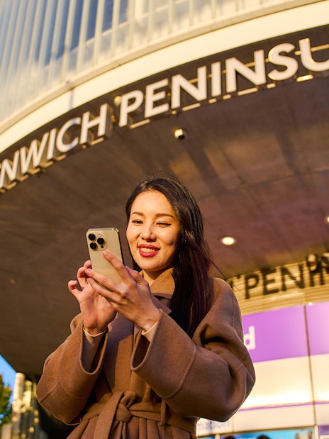 Guest using phone at Greenwich Peninsula, London near IFS Cloud Cable Car.
