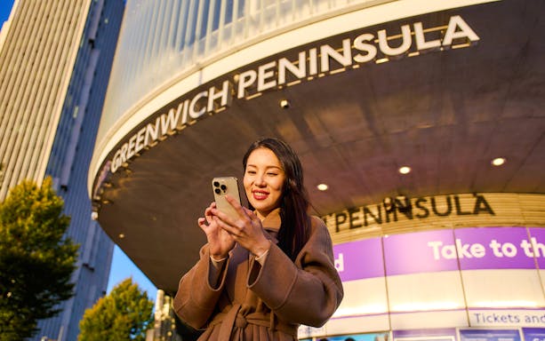 Guest using phone at Greenwich Peninsula, London near IFS Cloud Cable Car.