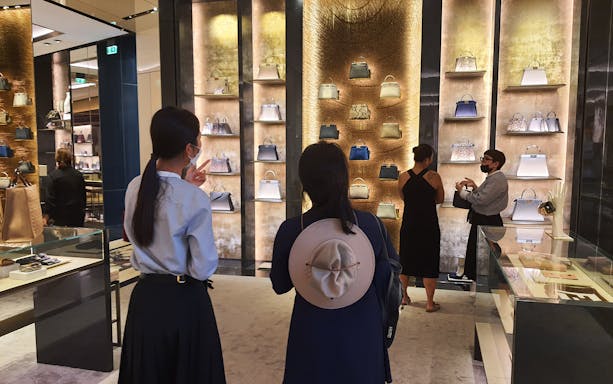 Visitors exploring luxury handbags in a Rome fashion house during a guided tour.