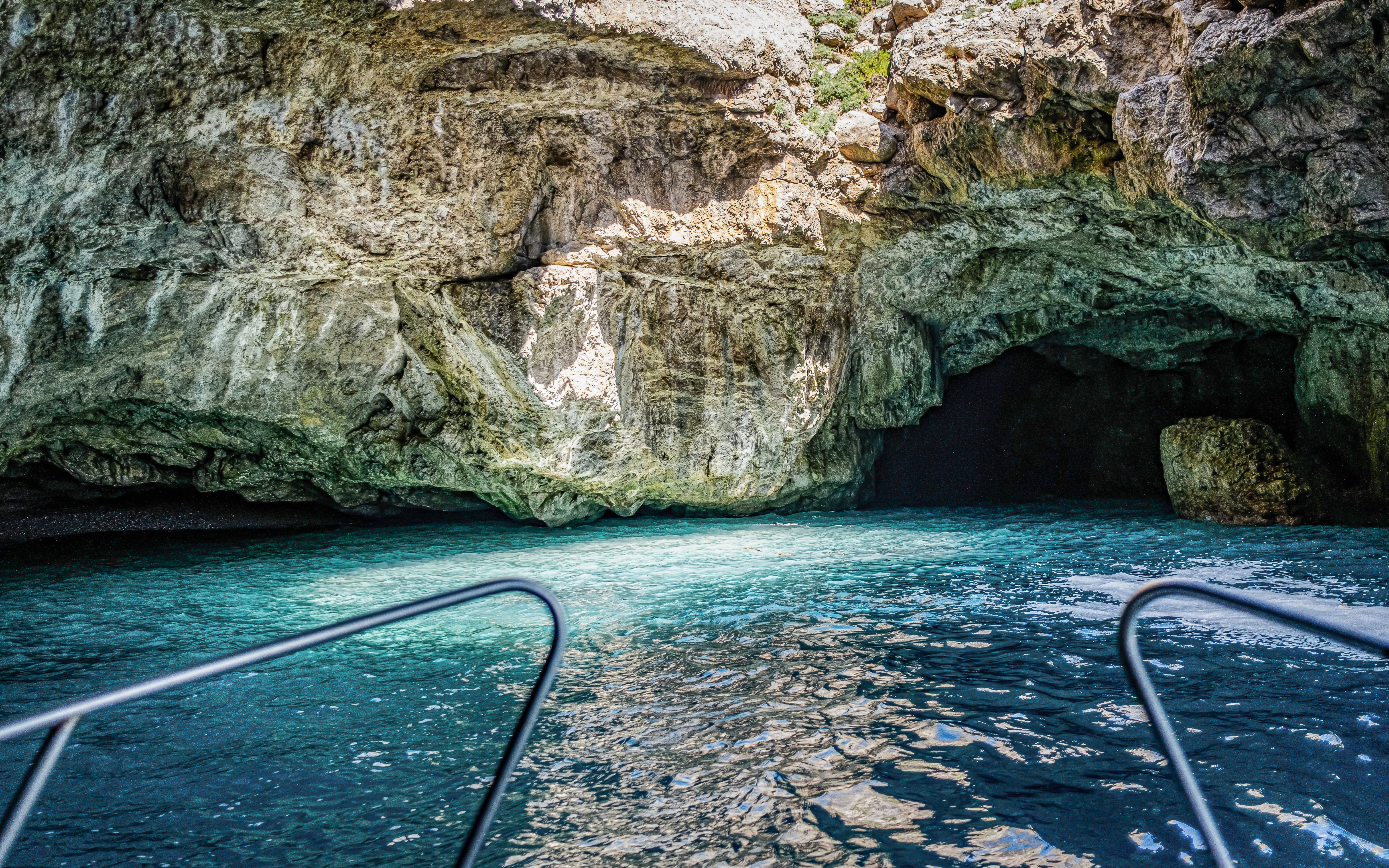 Boat entering the Camel Cave in Marettimo, Egadi Islands, with clear blue water.
