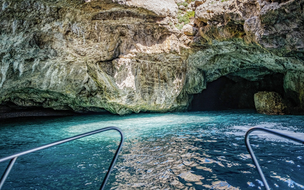 Boat entering the Camel Cave in Marettimo, Egadi Islands, with clear blue water.
