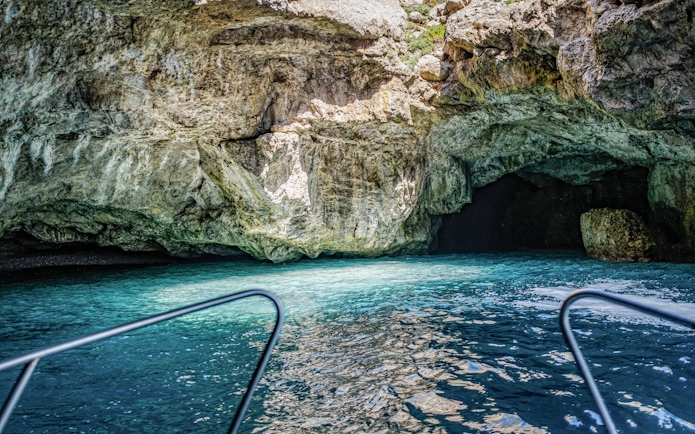 Boat entering the Camel Cave in Marettimo, Egadi Islands, with clear blue water.