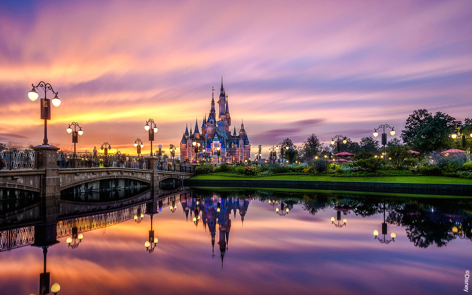 Shanghai Disney castle at sunset with reflections in the water.