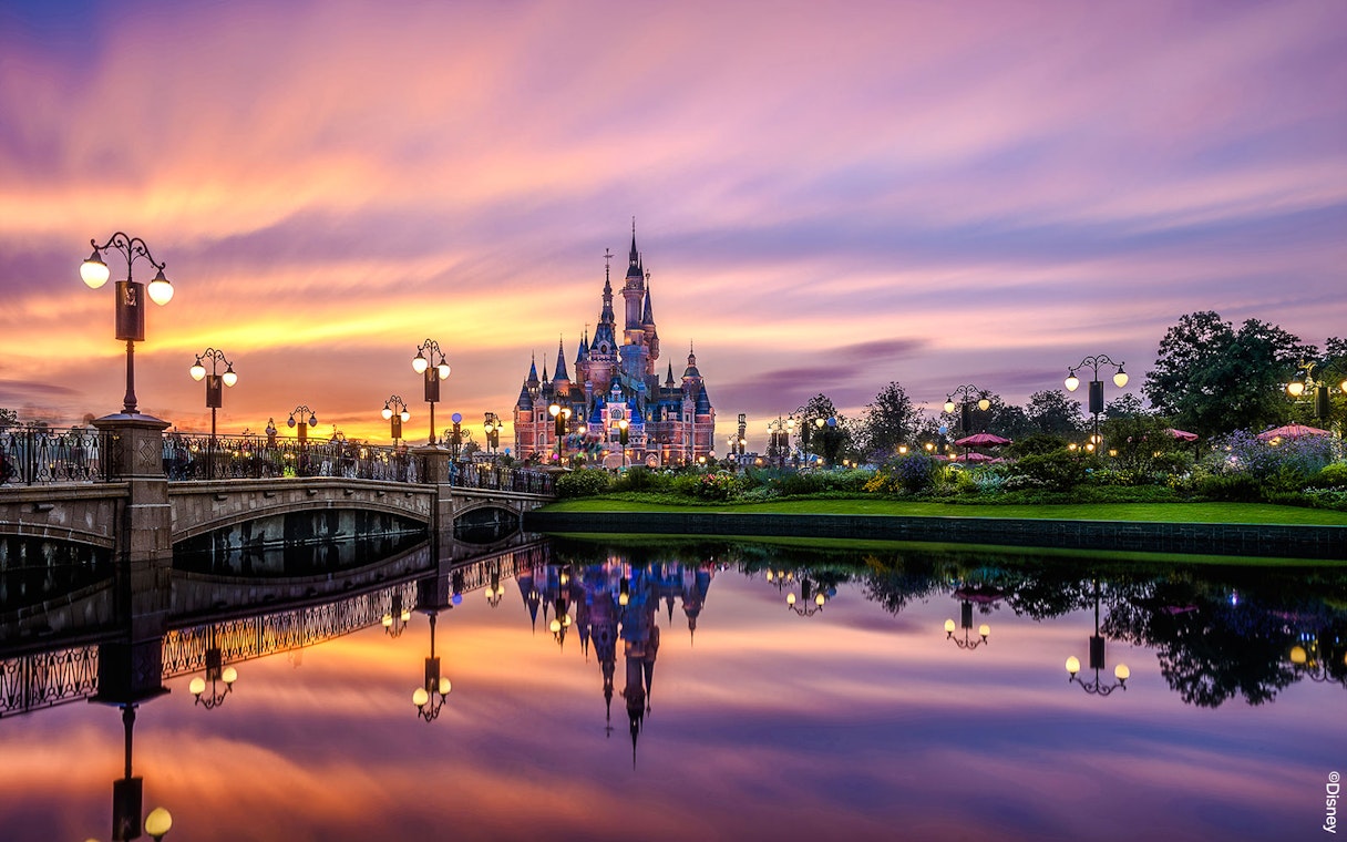 Shanghai Disney castle at sunset with reflections in the water.