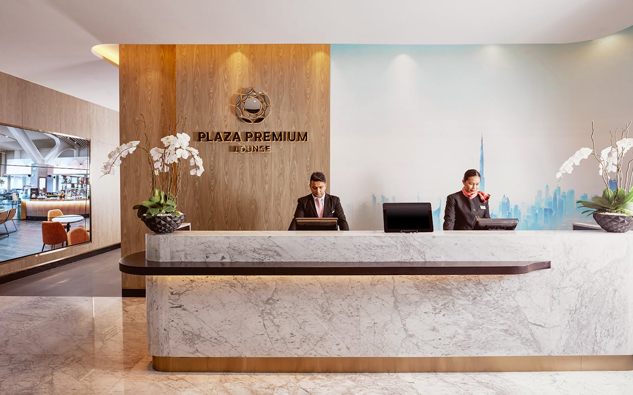 Plaza Premium Lounge reception at Dubai International Airport with staff at the desk.