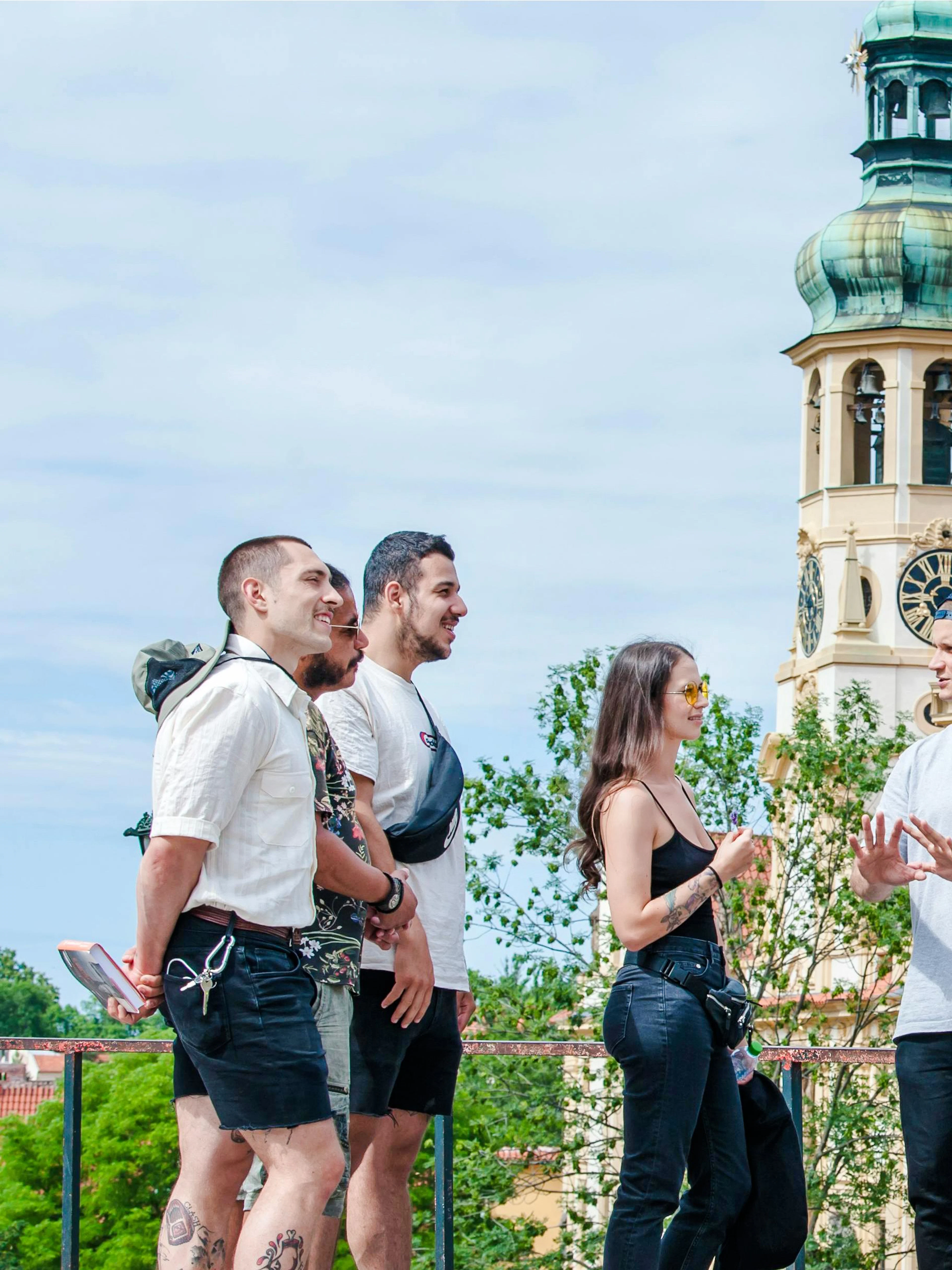 Guests exploring near Prague Castle with a view of a historic clock tower.