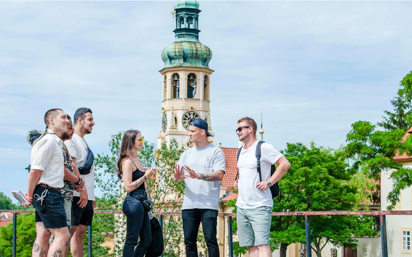 Guests exploring near Prague Castle with a view of a historic clock tower.