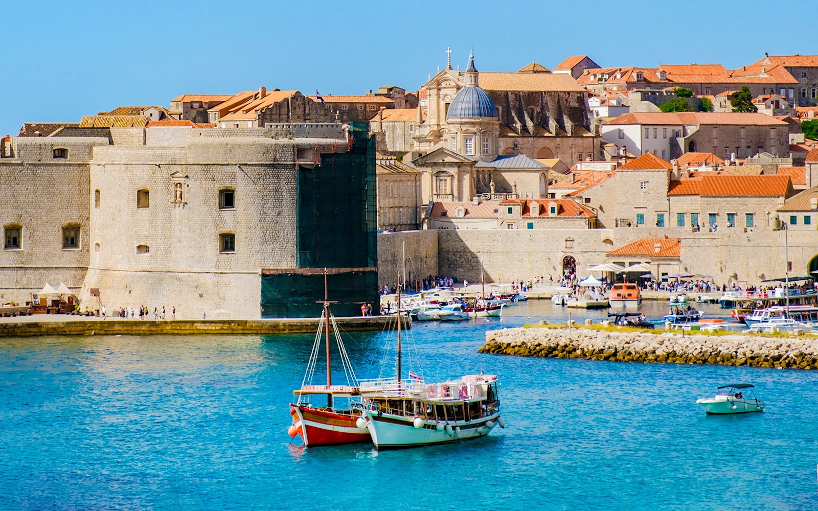 Boats in front of Dubrovnik's old town walls and historic buildings.