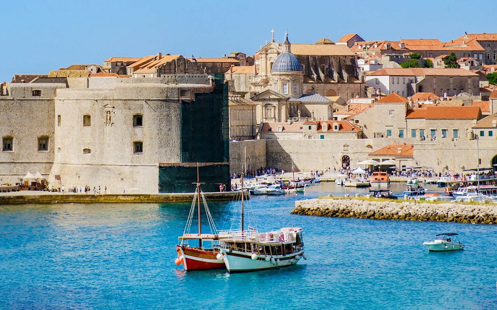 Boats in front of Dubrovnik's old town walls and historic buildings.
