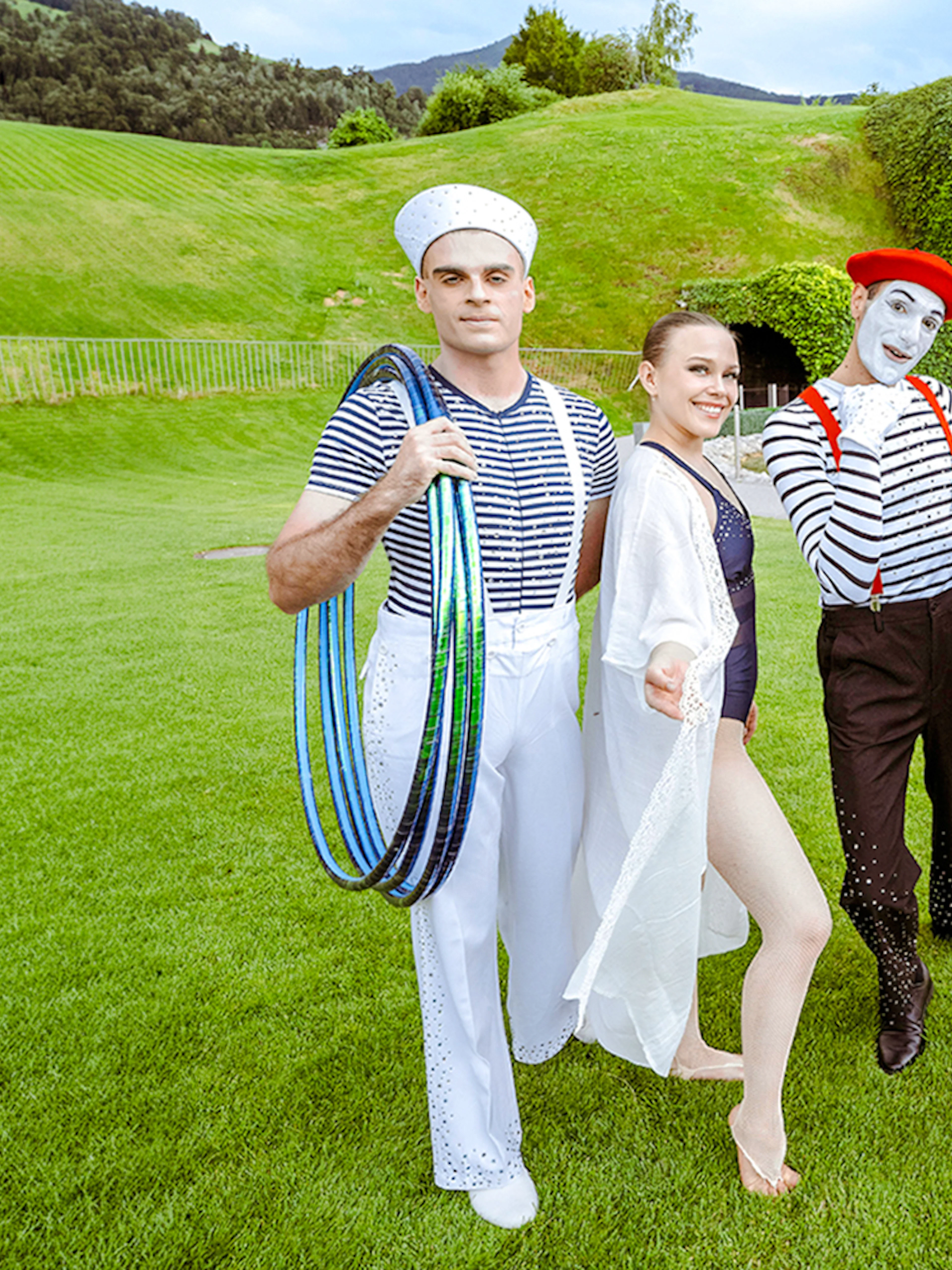 Performers in colorful costumes at Swarovski Crystal Worlds, Innsbruck, with the iconic grass-covered head sculpture.