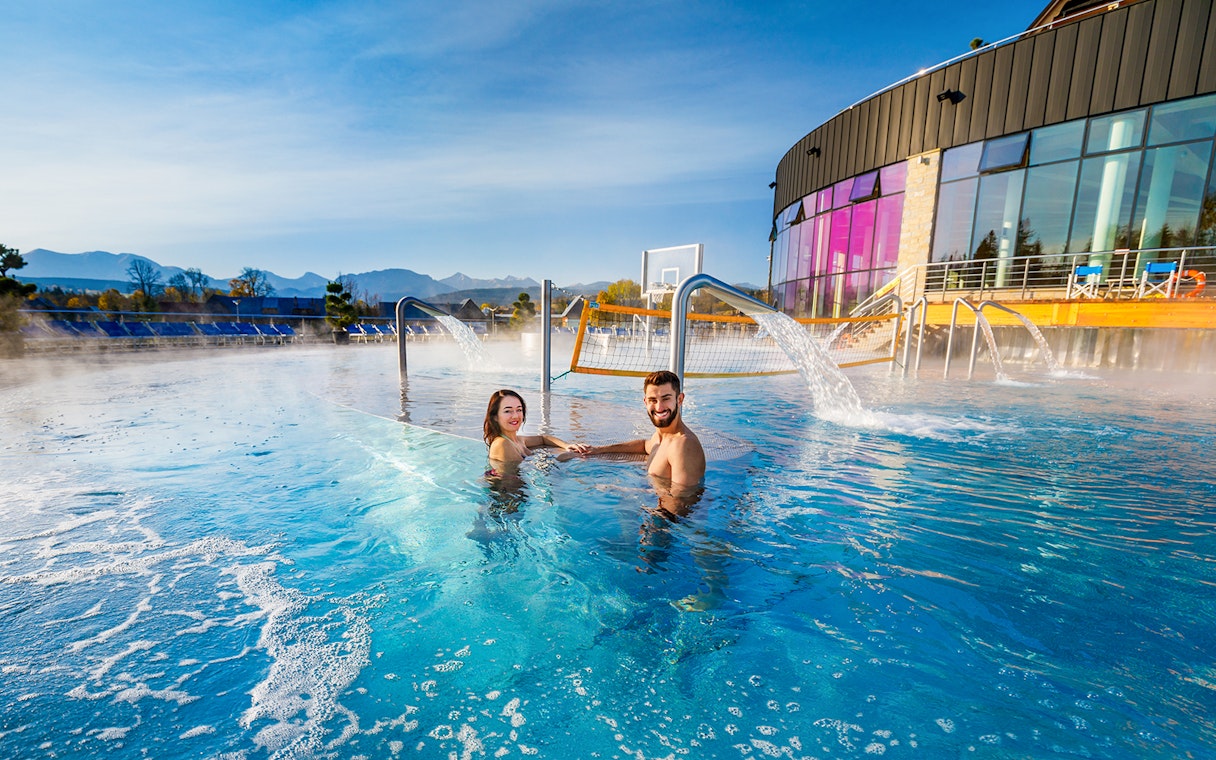 Tourists enjoying Chocholow Thermal Baths with mountain view.