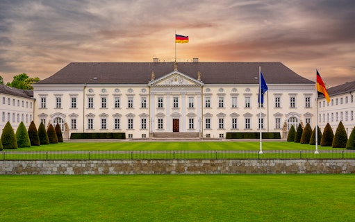 Bellevue Palace in Berlin, Germany, with German flags and manicured gardens.