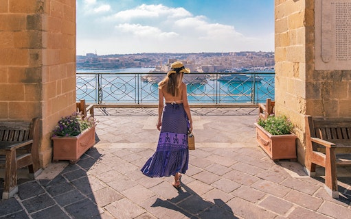 Visitor overlooking Valletta harbor from Upper Barrakka Gardens, Malta.