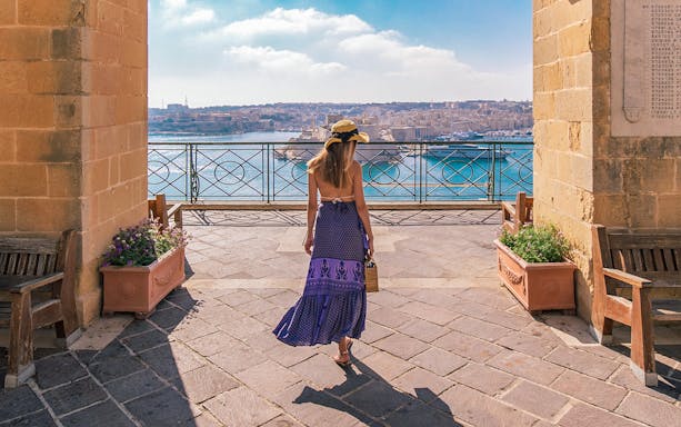 Visitor overlooking Valletta harbor from Upper Barrakka Gardens, Malta.