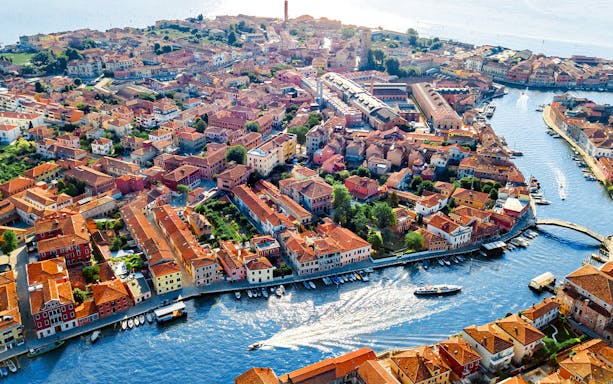 Aerial view of Murano island with canals and colorful buildings during helicopter tour over the lagoon.