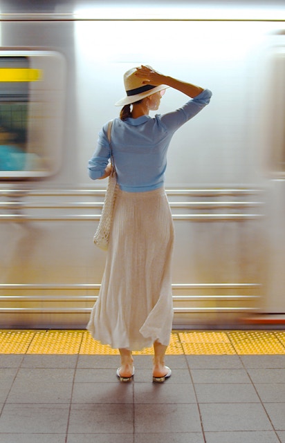 Girl standing on a railway platform as a train passes by.