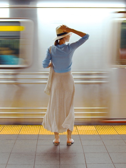 Girl standing on a railway platform as a train passes by.