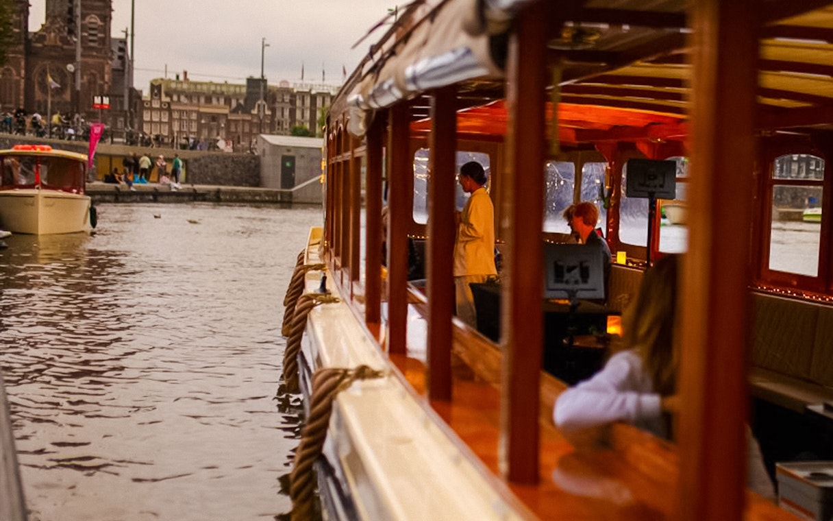 Luxury canal cruise in Amsterdam during Light Festival with passengers inside.