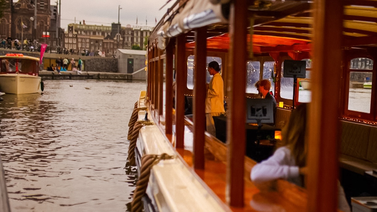 Luxury canal cruise in Amsterdam during Light Festival with passengers inside.