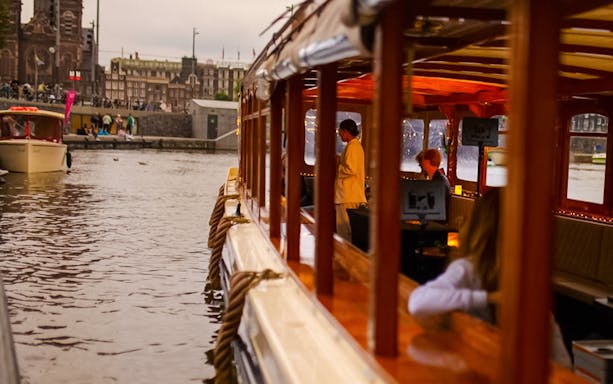 Luxury canal cruise in Amsterdam during Light Festival with passengers inside.