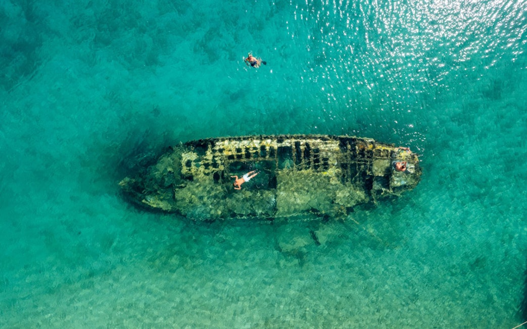 Shipwreck in clear waters near Split, Croatia, with snorkelers exploring.