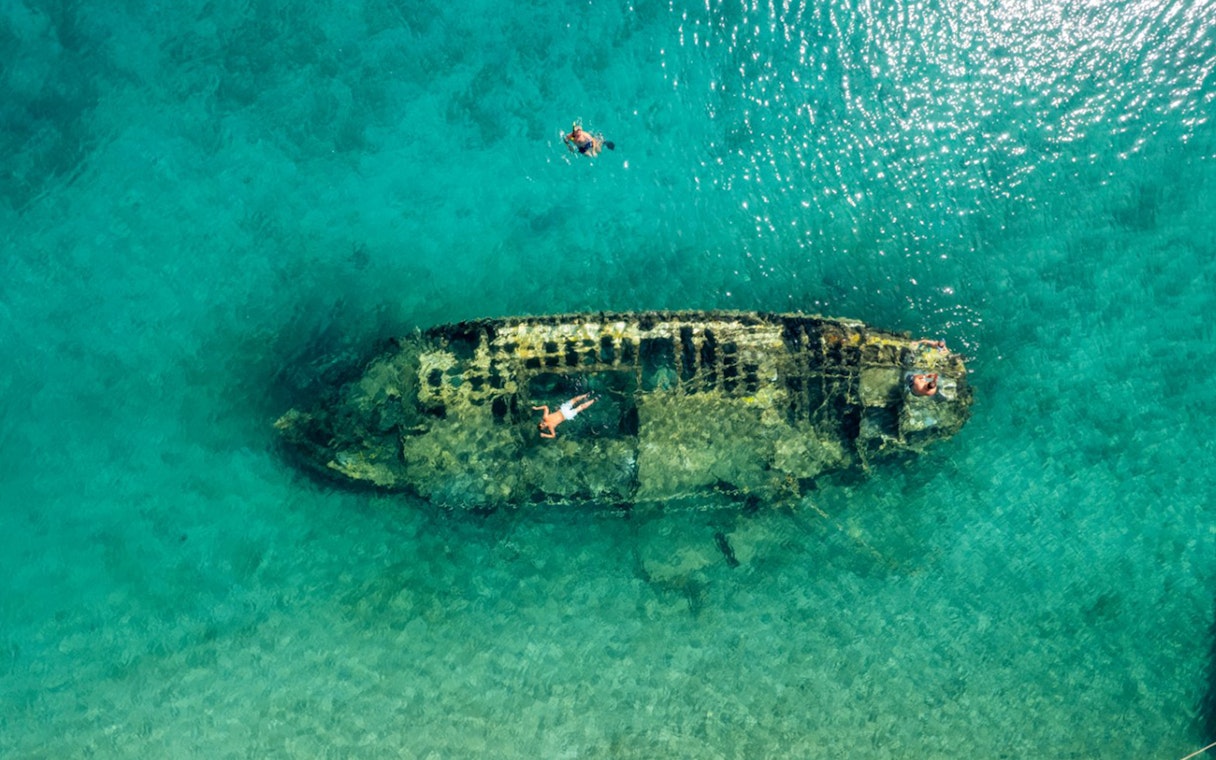 Shipwreck in clear waters near Split, Croatia, with snorkelers exploring.