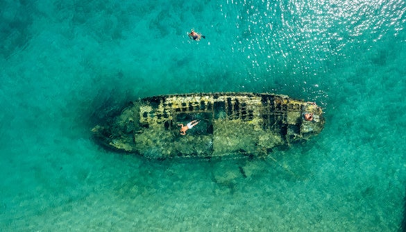 Shipwreck in clear waters near Split, Croatia, with snorkelers exploring.