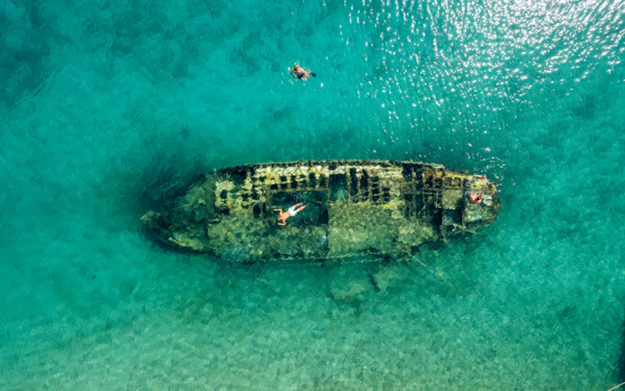 Shipwreck in clear waters near Split, Croatia, with snorkelers exploring.
