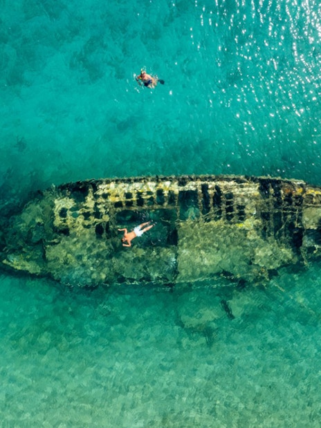 Shipwreck in clear waters near Split, Croatia, with snorkelers exploring.