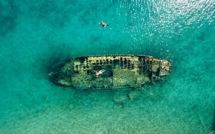 Shipwreck in clear waters near Split, Croatia, with snorkelers exploring.