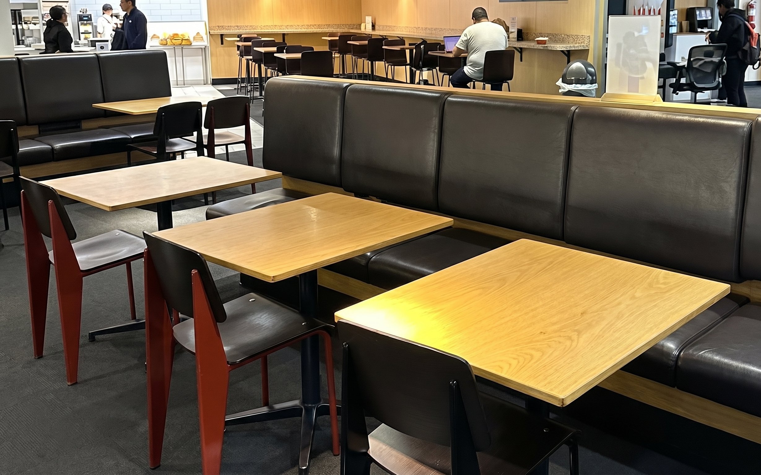 Seating area at HelloSky Lounge, JFK Terminal 4, New York, with tables and chairs.
