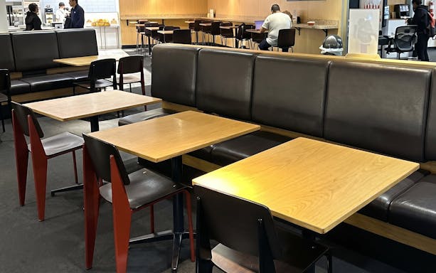 Seating area at HelloSky Lounge, JFK Terminal 4, New York, with tables and chairs.