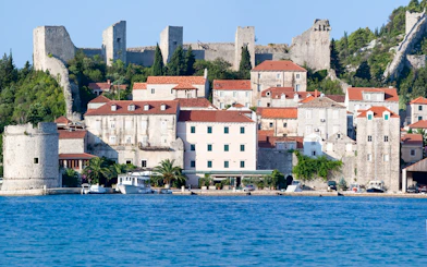 Stone walls and historic buildings in Town Ston near Dubrovnik, Croatia, viewed from the water.