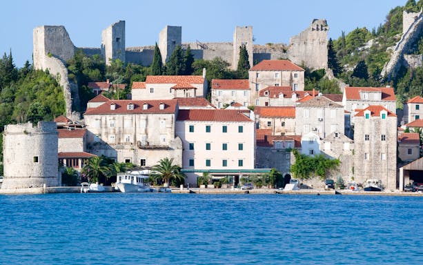 Stone walls and historic buildings in Town Ston near Dubrovnik, Croatia, viewed from the water.