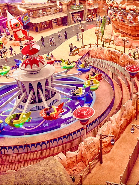 Aerial view of a colorful ride at Warner Bros. World Abu Dhabi with visitors enjoying the attraction.