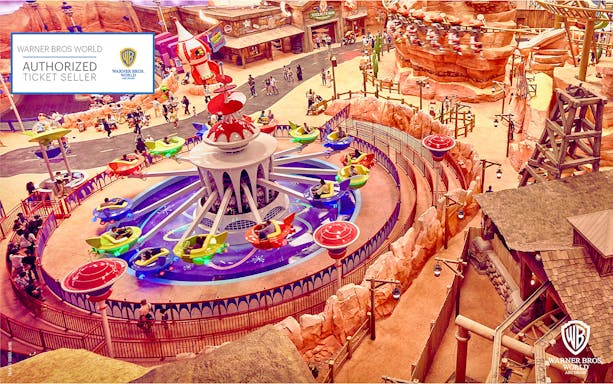 Aerial view of a colorful ride at Warner Bros. World Abu Dhabi with visitors enjoying the attraction.
