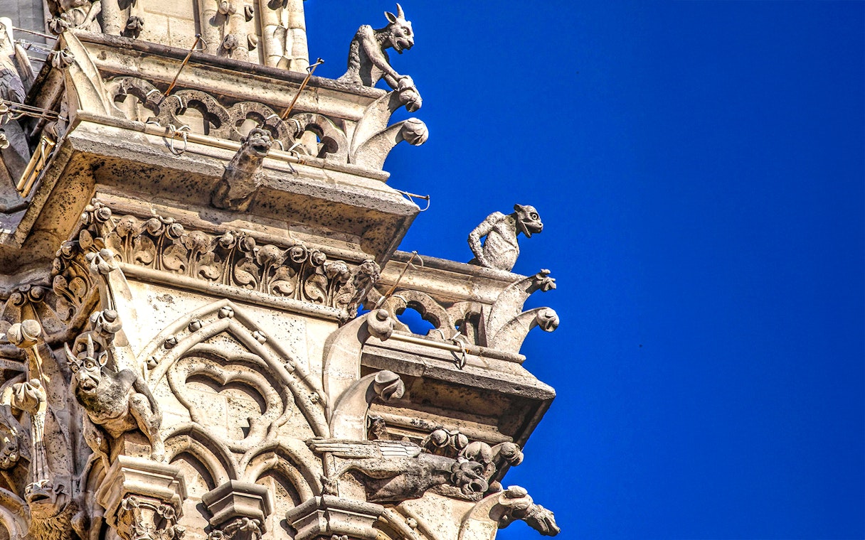 Notre-Dame Cathedral gargoyles against blue sky, Paris tour.