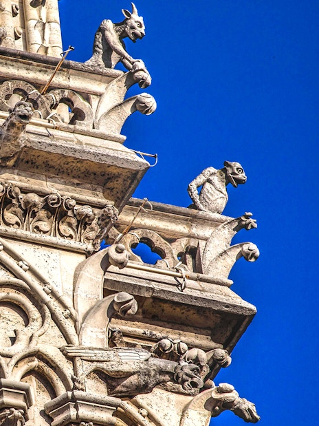 Notre-Dame Cathedral gargoyles against blue sky, Paris tour.