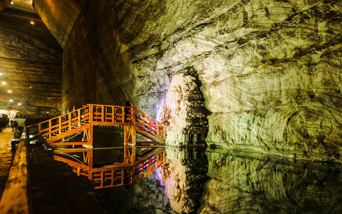 Guests walking on a wooden bridge inside Slanic Salt Mine, Romania.