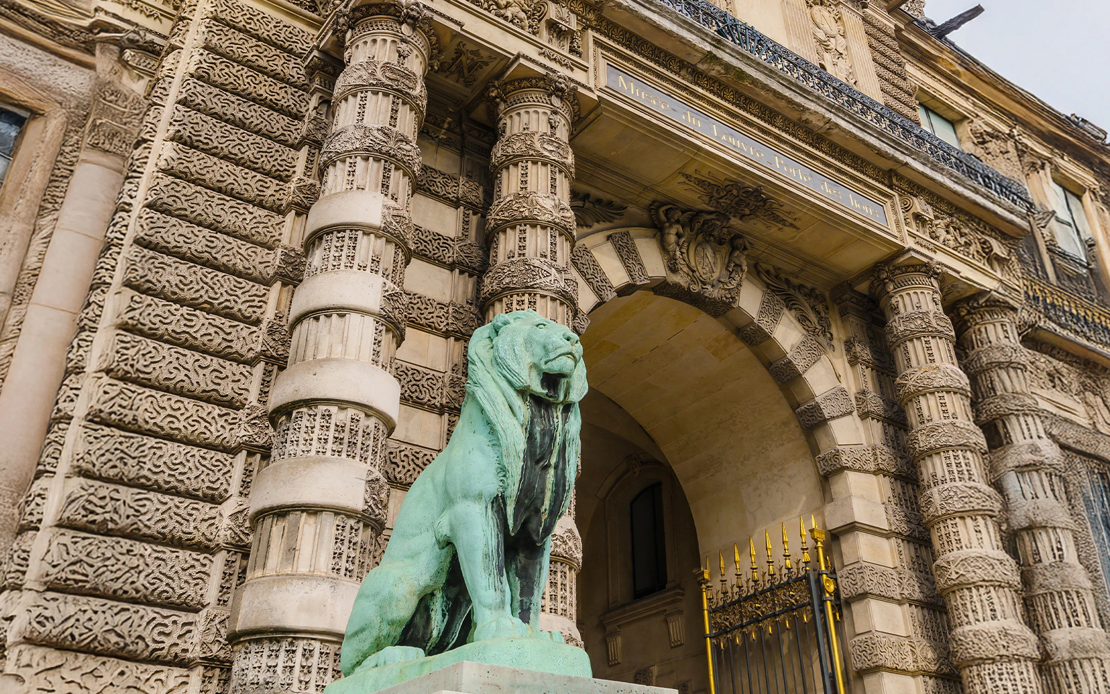 Louvre Museum Lions Gate with ornate stonework and lion statue in Paris.