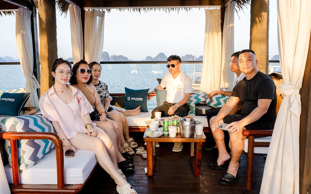 People relaxing with drinks on a dolphin cruise with ocean view in the background.