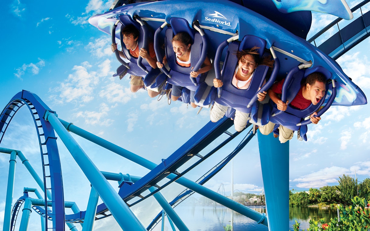 Riders on Manta roller coaster at SeaWorld, experiencing a thrilling loop.